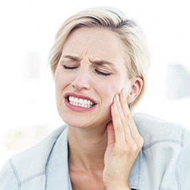 Grimacing woman holding cheek